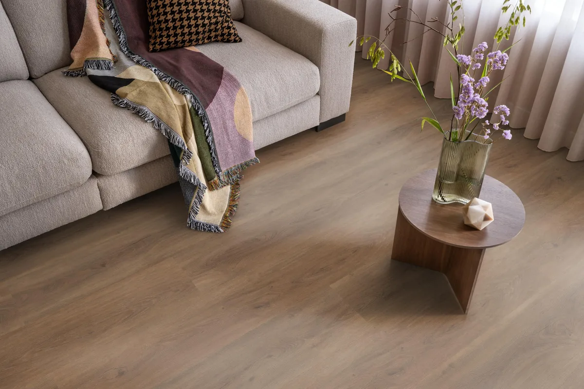 Parramatta / Robusto warm brown, plak pvc in een woonkamer, met een beige bank en een ronde bijzettafel met bloemen