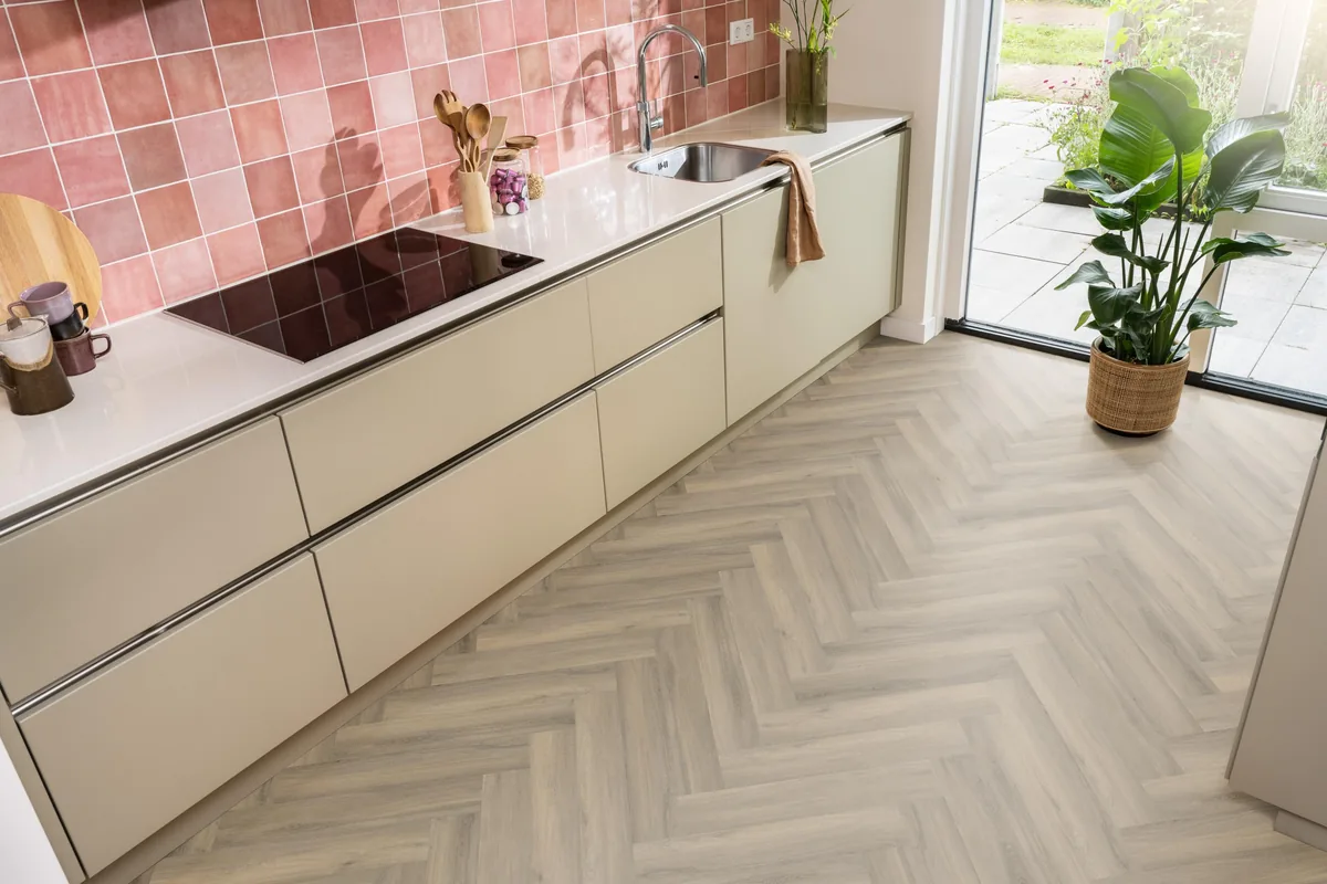 YUP / Spigato light brown, visgraat plak pvc in een keuken met een roze tegelwand en openslaande tuindeuren