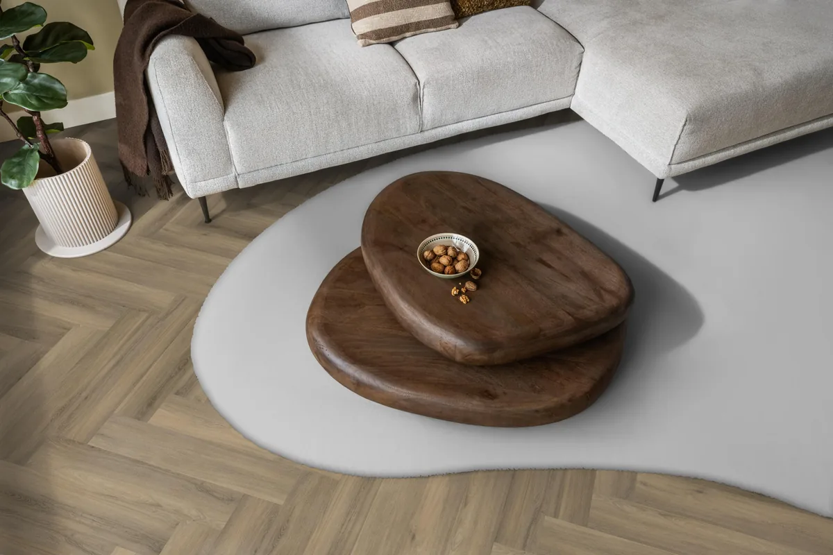 YUP / Spigato light brown, visgraat plak pvc in een woonkamer, met een lichte hoekbank en een wit vloerkleed