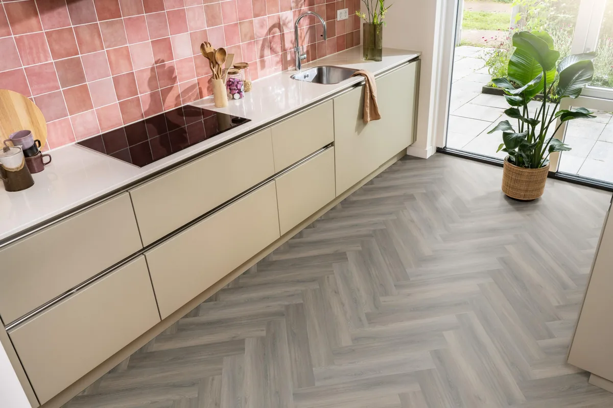 YUP / Spigato dark grey, visgraat plak pvc in een keuken met een roze tegelwand en openslaande tuindeuren