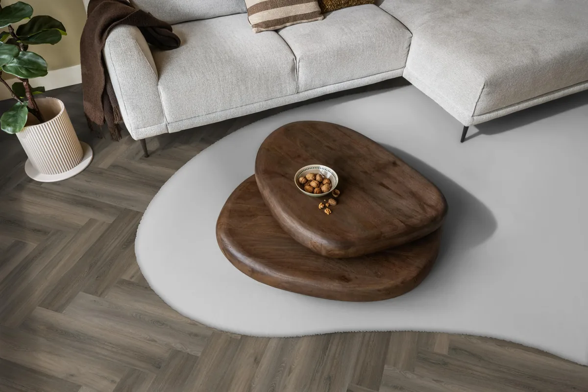 YUP / Spigato dark grey, visgraat plak pvc in een woonkamer, met een lichte hoekbank en een wit vloerkleed