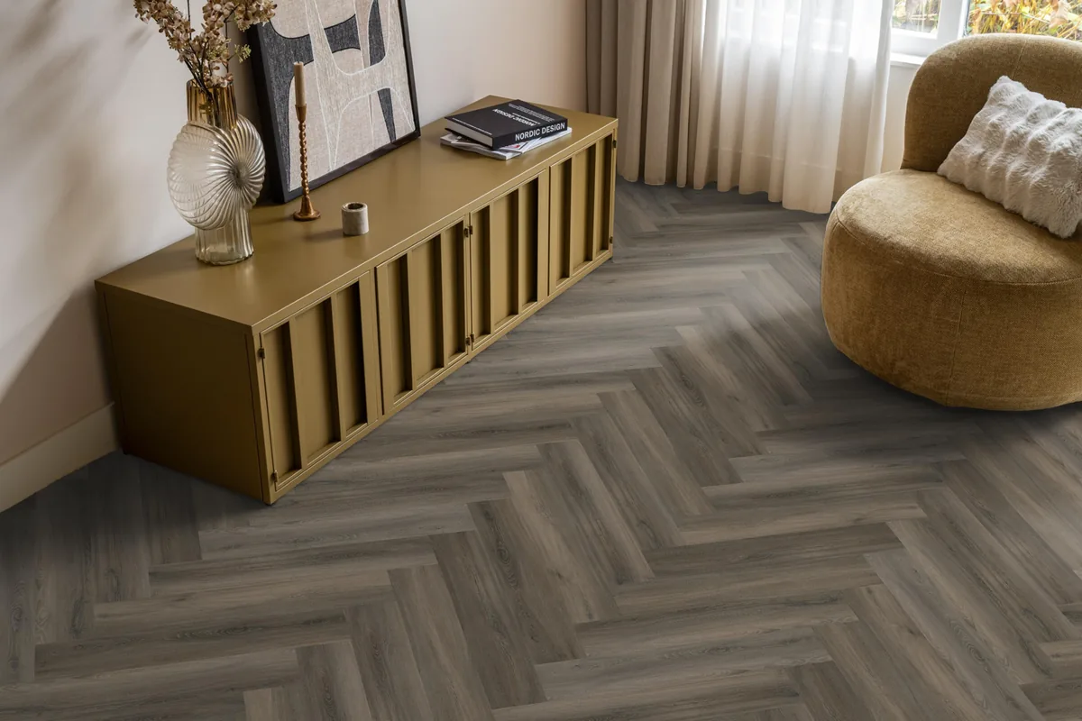 YUP / Spigato dark grey, visgraat plak pvc in een woonkamer, met een okergeel dressoir en een ronde fauteuil