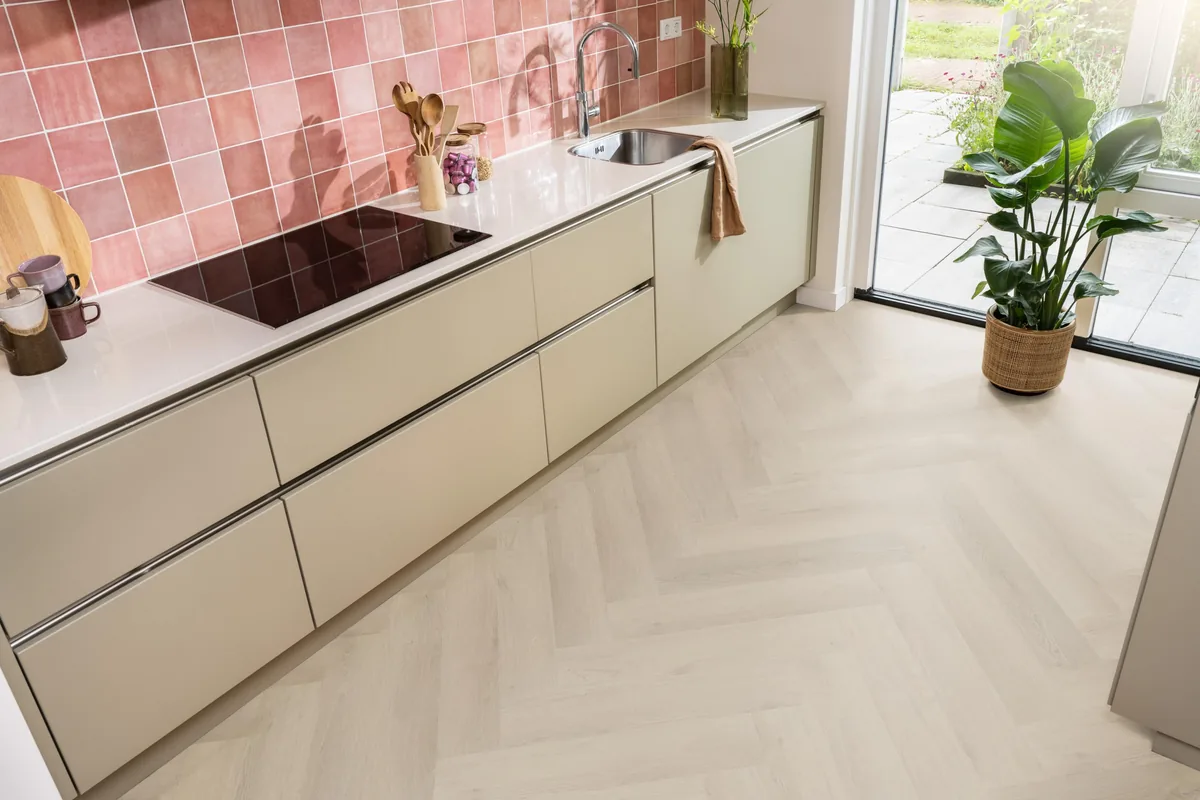 Merton / Navaro beige, visgraat plak pvc in een keuken met een roze tegelwand en openslaande tuindeuren