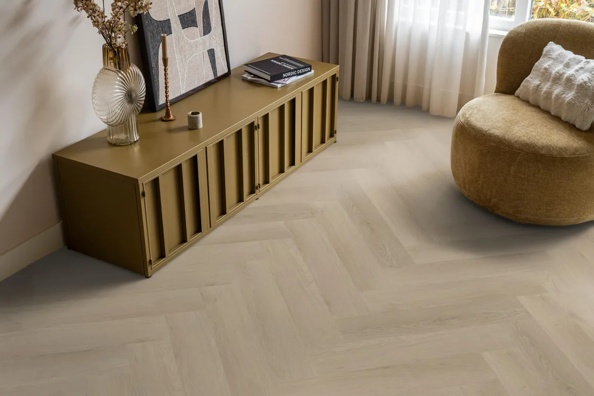 Merton / Navaro beige, visgraat plak pvc in een woonkamer, met een okergeel dressoir en een ronde fauteuil