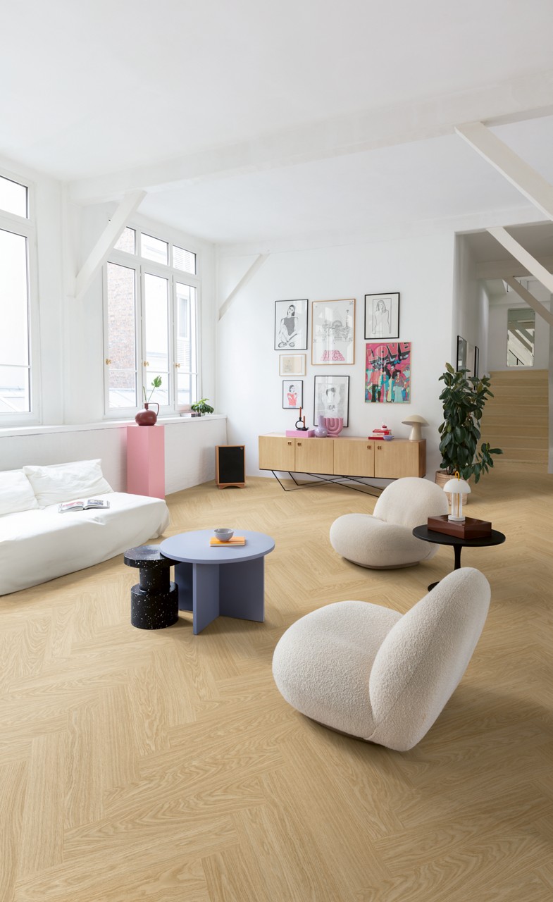 Interieurfoto bij Quick-Step Pure eik blush AVHBU40359: visgraatvloer in een lichte woonkamer met een trap op de achtergrond.
