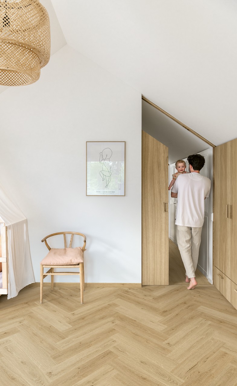 Interieurfoto bij Quick-Step Botanisch beige AVHBU40362: visgraatvloer in een lichte hal met een houten trap.