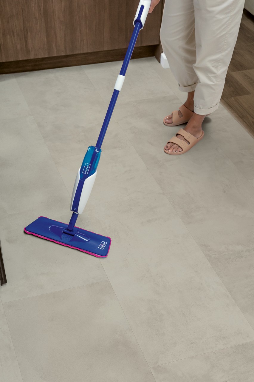 Interieurfoto bij Quick-Step Grijs beton MUS5488: grijze tegelvloer tijdens het schoonmaken.