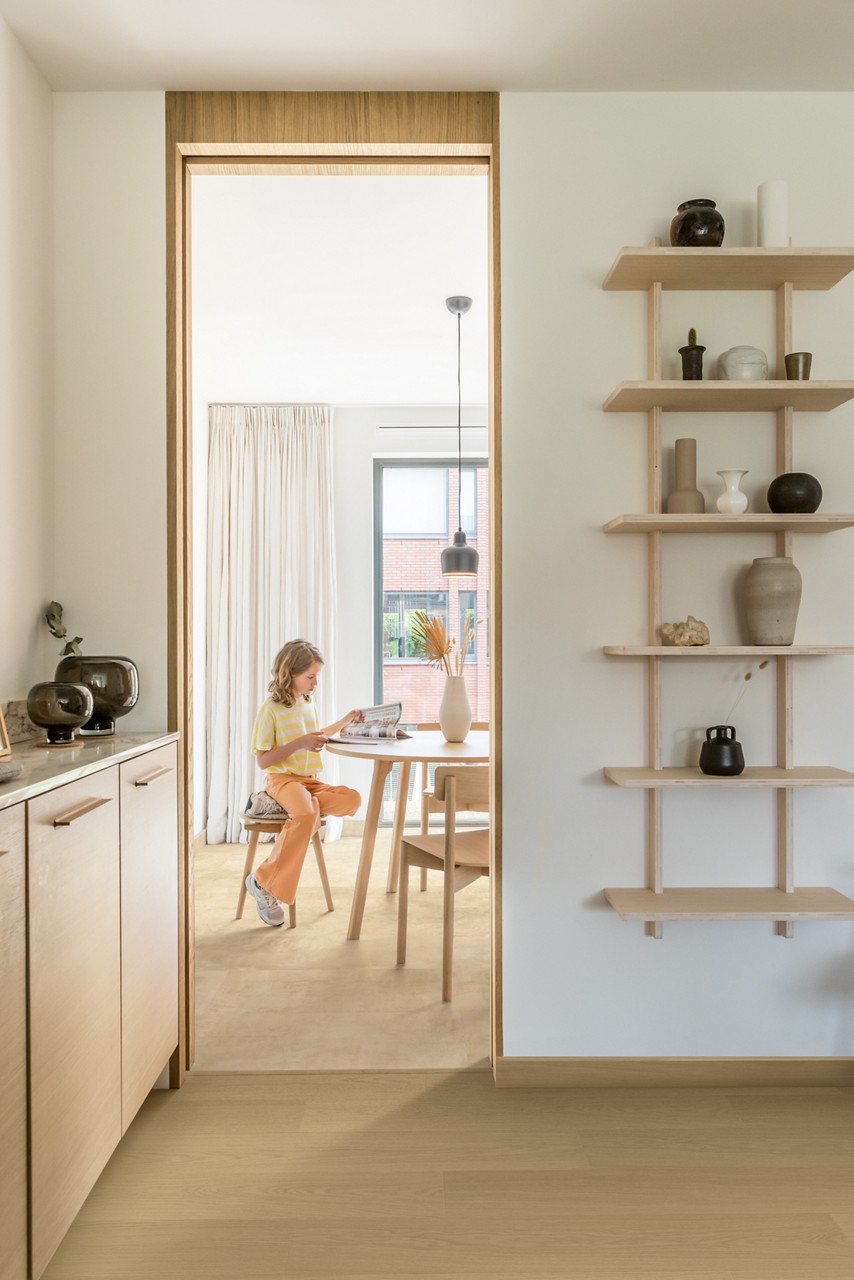 Interieurfoto bij Quick-Step Zandsteen MUS5489: doorkijk vanuit een lichte tegelvloer naar een kamer met houten vloer.