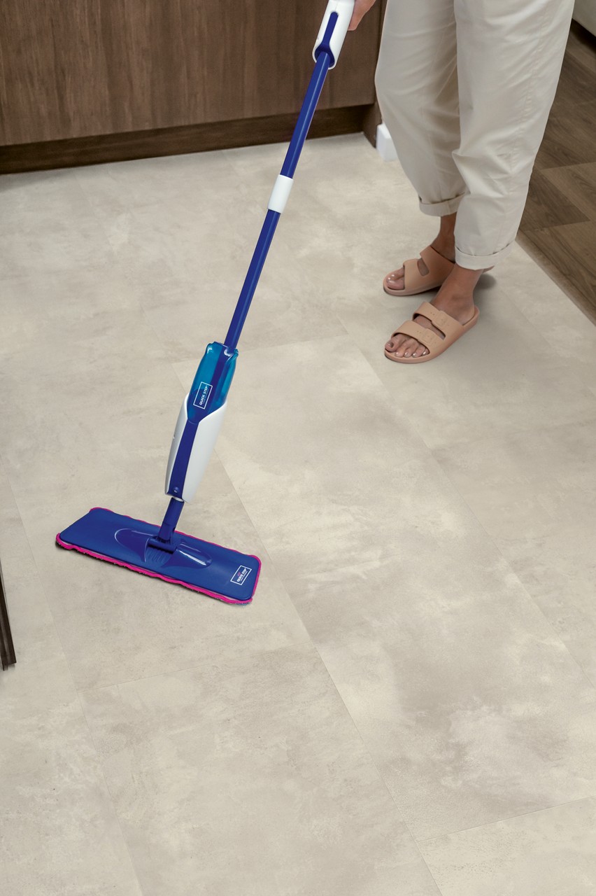 Interieurfoto bij Quick-Step Gevlekt beton MUS5491: lichte tegelvloer tijdens het schoonmaken.