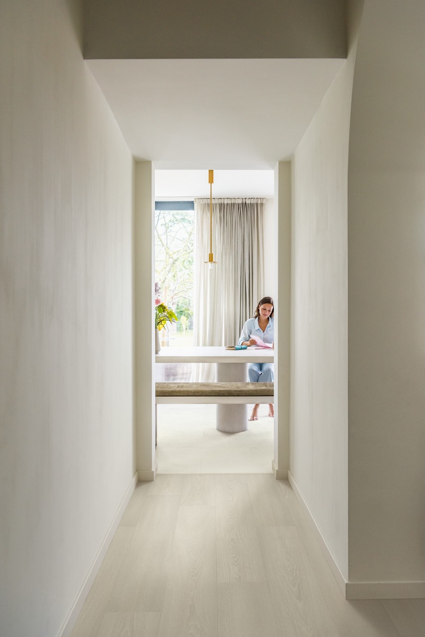 Interieurfoto bij Quick-Step Premium witte eik SIG4757: lichte houten vloer in een gang met een aangrenzende kamer.